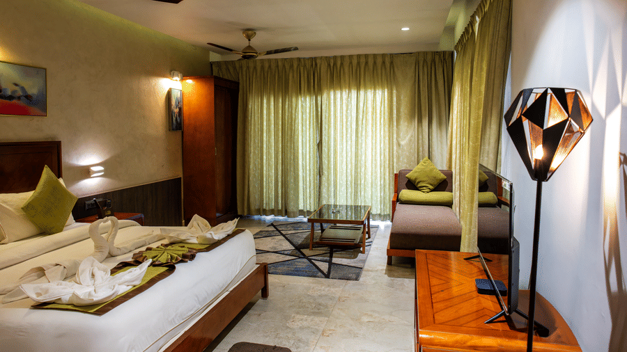 Deluxe Room with double bed, green curtains, and ceiling fan at Hotel Sonar Bangla, Taki.