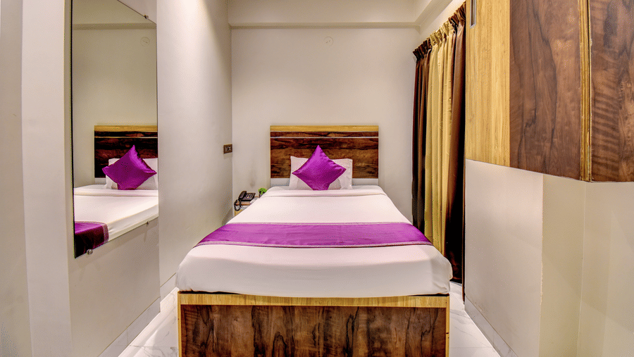 Classic Single Room with bed, purple linen, wooden headboard and full-length mirror reflection at VITS Select Kharadi Pune