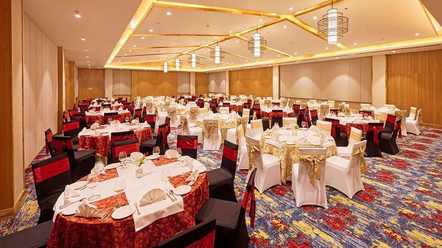 Banquet hall setup with red and white chair covers and decorative lighting - Royal Tulip, Chitwan