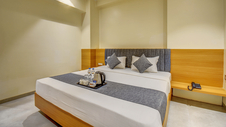 Deluxe Room at VITS Select Nashik Hotels & Resorts featuring tea and coffee maker on a tray placed on the bed runner of a plush bed
