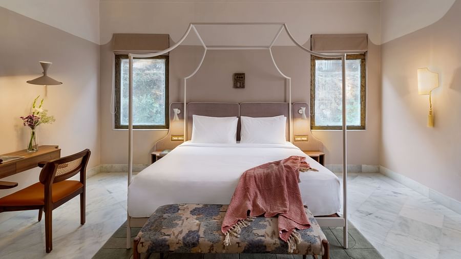 A double bed with a study table next to it inside Superior Room - Manuscript - Jhilwara Haveli, Udiapur