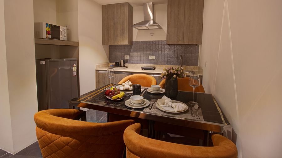 overview of the kitchenette with a dining table and kitchen area in the background inside Two bedroom Executive Suite - Rhythm Gurugram