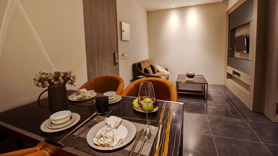 a dining table with sofas and a coffee table in the background inside the living room of Two bedroom Executive Suite - Rhythm Gurugram