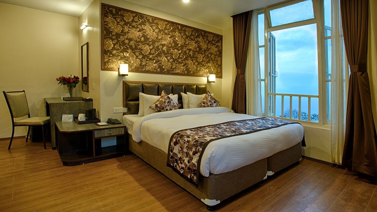 Elegant hotel room at Voyage The Aryan Regency with ornate floral wallpaper, comfortable bed, work desk, and large windows overlooking the exterior