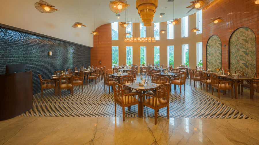 Restaurant dining area with wooden tables and chairs, pendant lights, decorative walls and large windows.