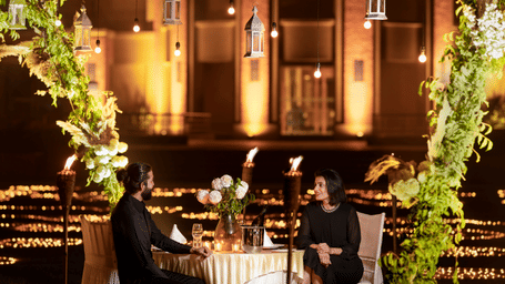 A couple enjoying dinner in an open-air setting surrounded by lavish decoration at Nirvana Luxury Hotel, Ludhiana.