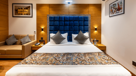 The best hotel in Sumerpur Rajasthan, Lords hotel, featuring its executive bedroom with a large bed, royal blue headboard, ambient lighting with sofas in the corner.