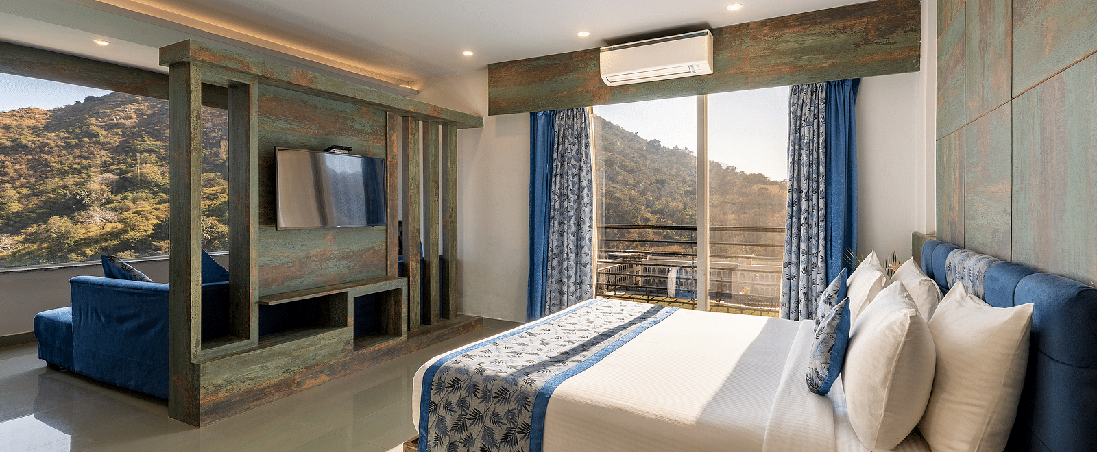 A bedroom with a made bed, patterned runner and a mountain view through the window - Via Lakhela Resort & Spa 