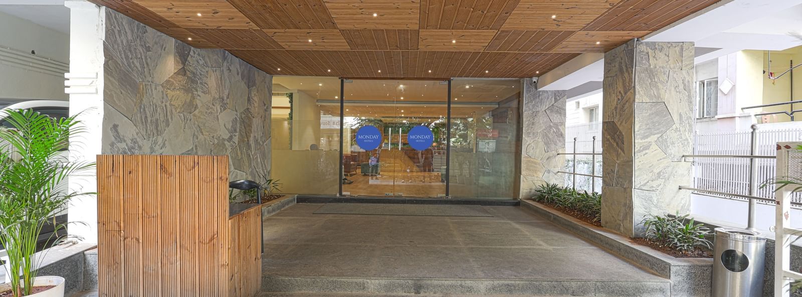 A covered driveway of Monday Hotels HITEC City, Hyderabad's entrance with glass walls.