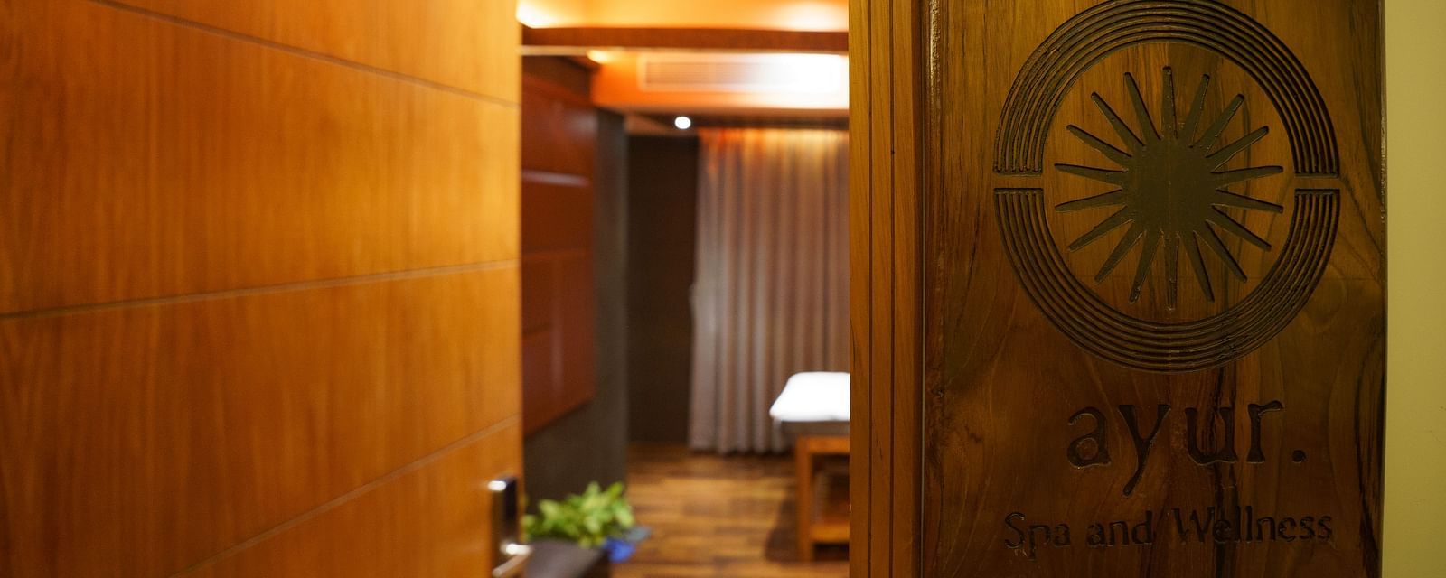 a glimpse of the spa seen from the outside at Coral Reef Hotel & Spa in Port Blair as the wooden board on the wall says Ayur Spa