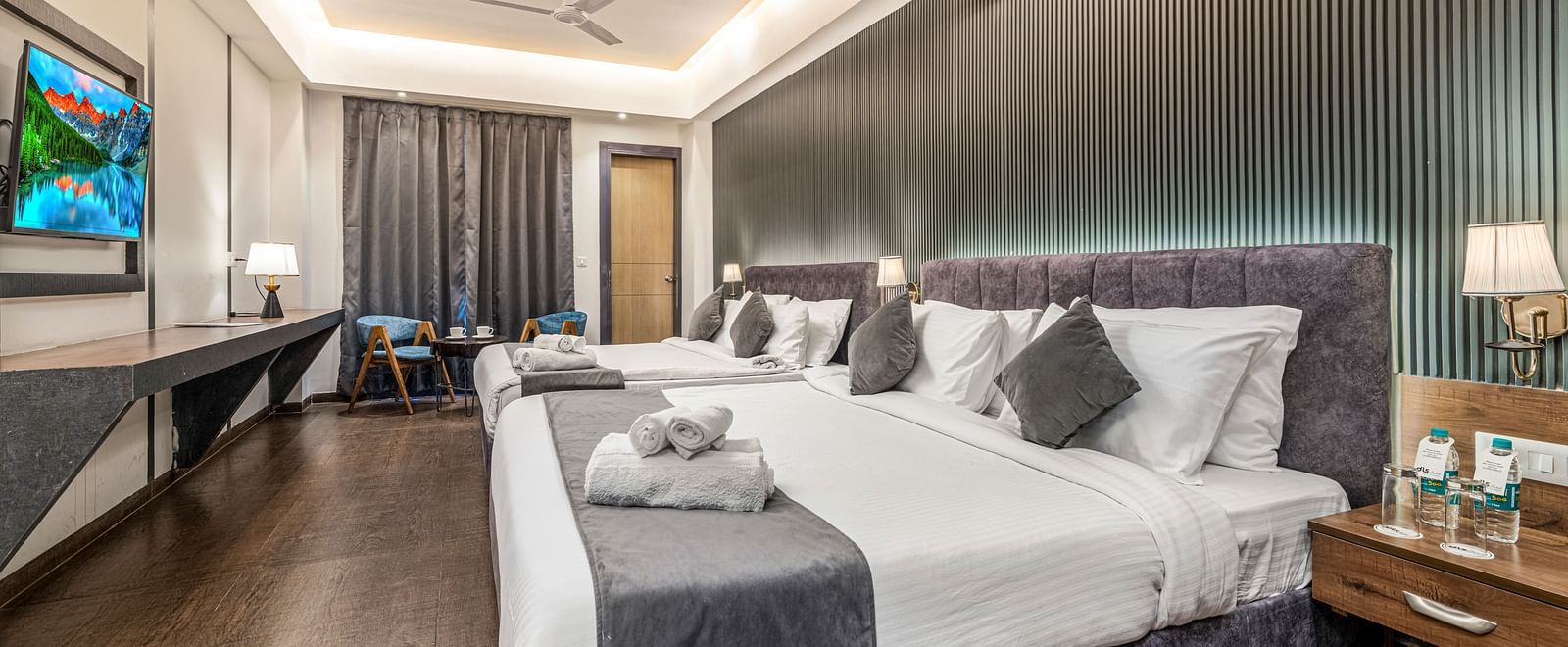 A shot of a room with two beds, bed side tables, a flat screen TV, and other room amenities - DLS Ganga Bliss, Haridwar
