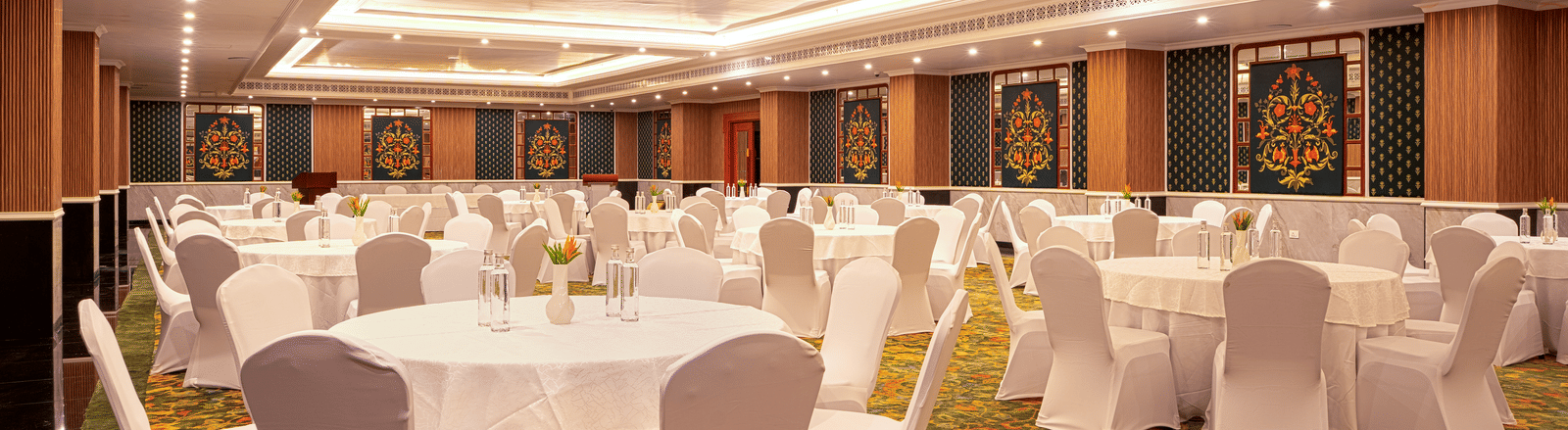 A large banquet hall set up with numerous circular tables draped in white cloths at MAYFAIR Bay Resort, Paradeep.