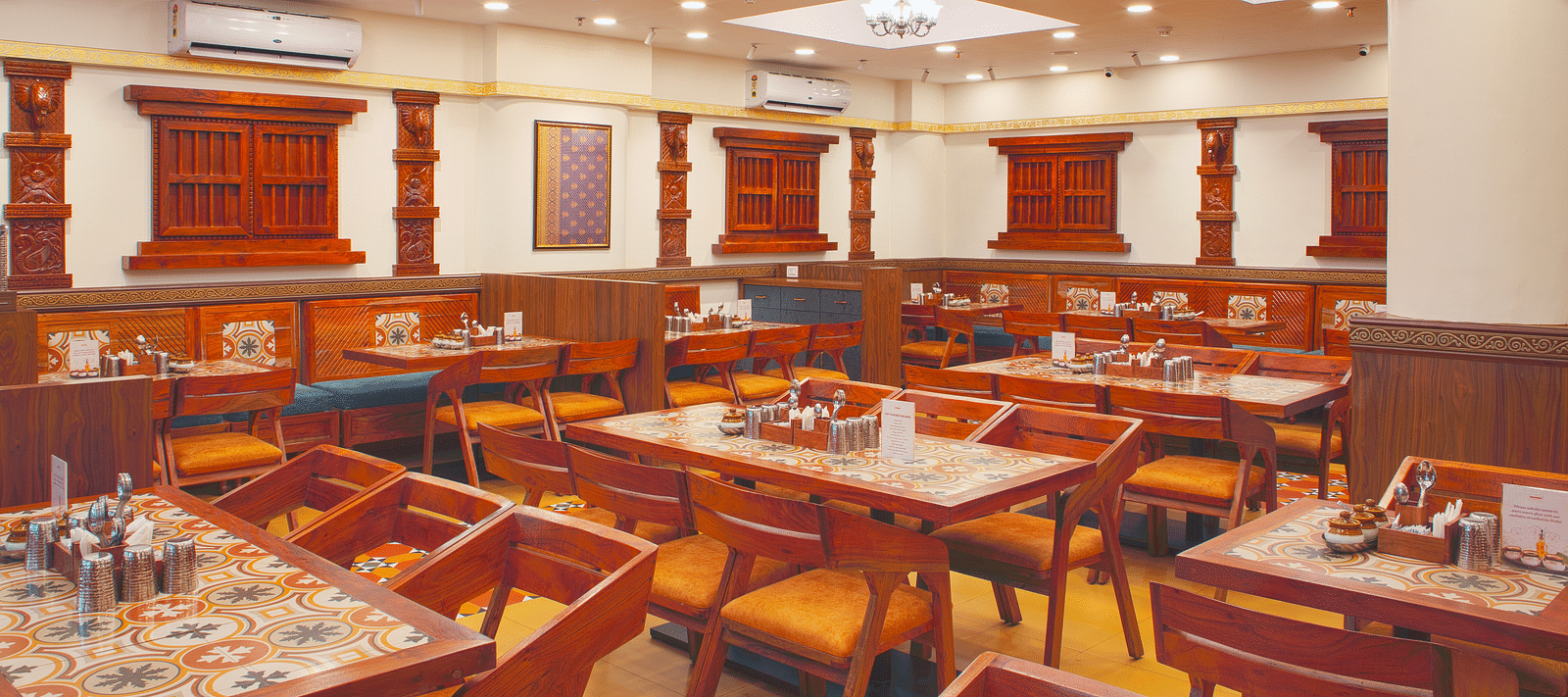 Elegant dining area with rich wooden furniture and modern lighting | Kamats India