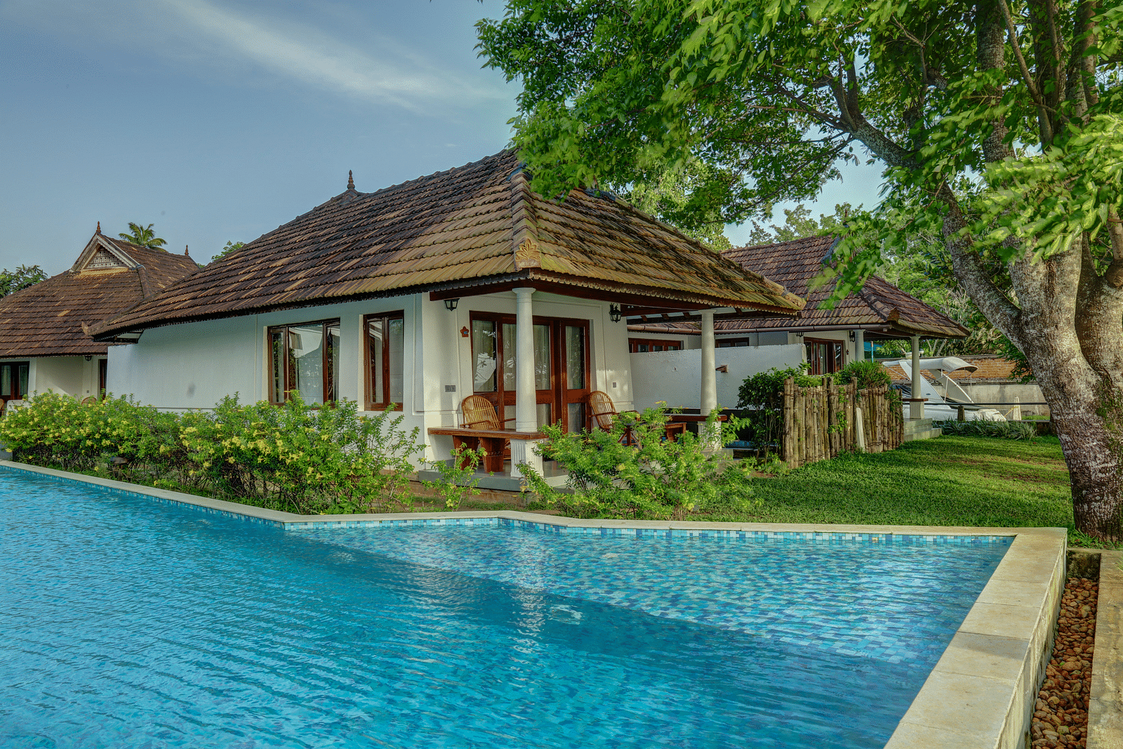 A cluster of cottages nestled around a central swimming pool - Rhythm Kumarakom