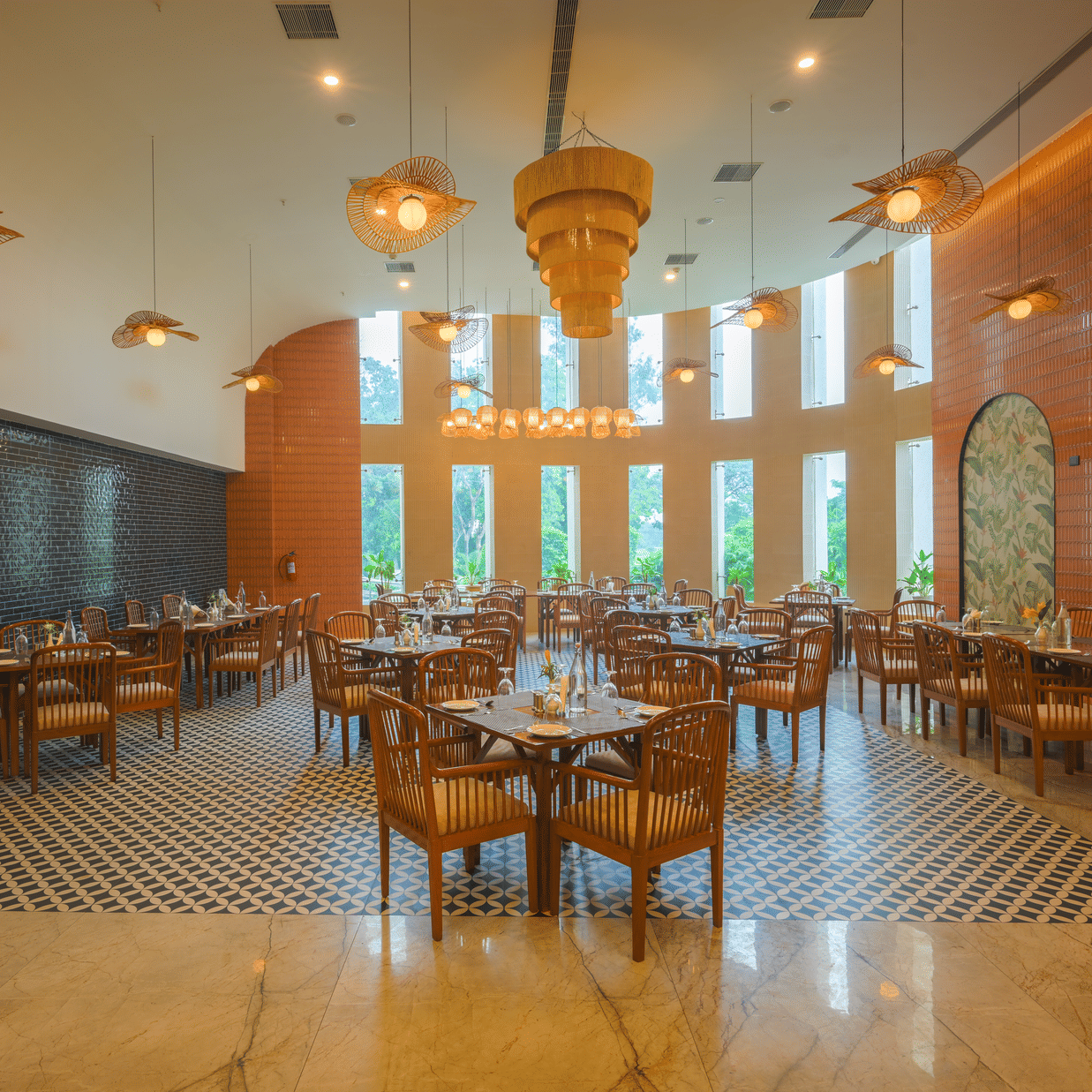 Restaurant dining area with wooden tables and chairs, pendant lights, decorative walls and large windows.