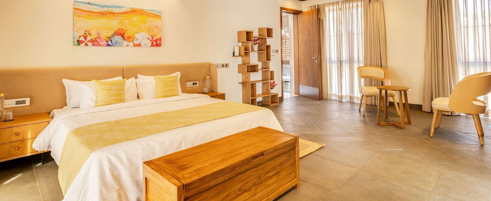 A cosy bedroom with a pitched wooden ceiling, a king-sized bed, soft yellow accents, and natural light filling the space - BluSalzz Villas - Alocassia, Anjuna