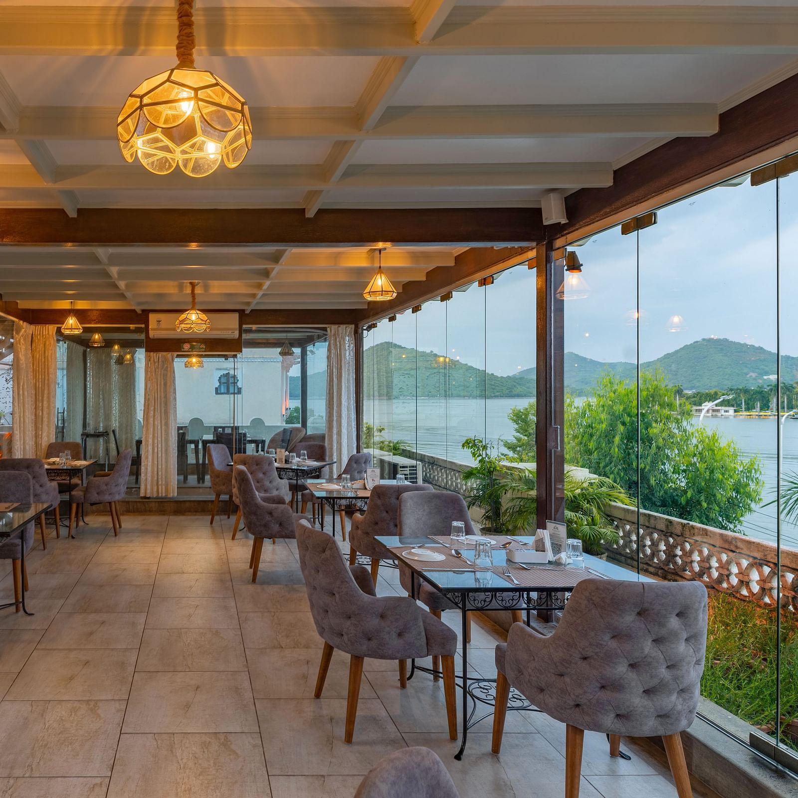 Restaurant area at Panna Vilas Palace showcases a four-seater table with wooden chairs, enhanced by warm lighting and the presence of potted plants | Panna Vilas Udaipur