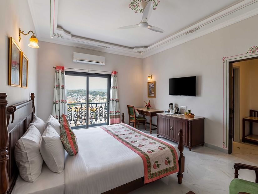 An overview of the suite with a king bed, tv and balcony at Superior Room - Maan Vilas by Stone Wood, Udaipur