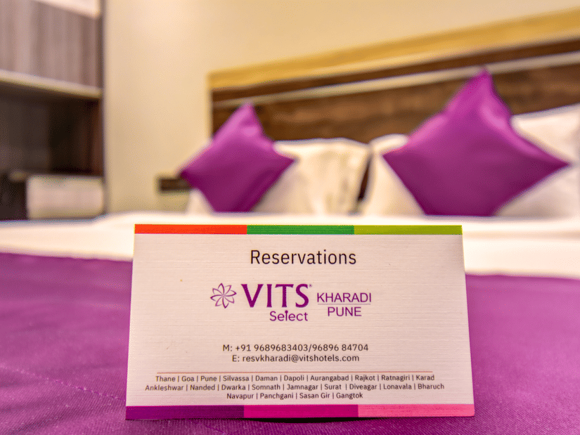 Super Deluxe Room king bed with purple accent runner featuring a reservation card at VITS Select Kharadi, Pune