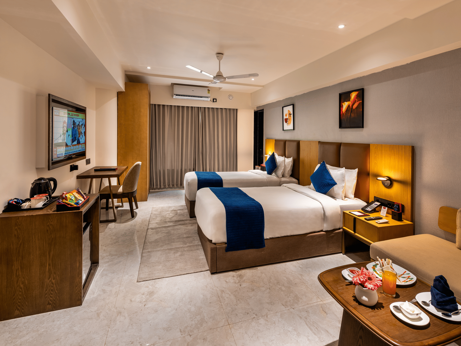 Elegantly furnished deluxe room with a king-sized bed, blue accent pillows, and warm lighting at Lords Studio Inn, Jamnagar.