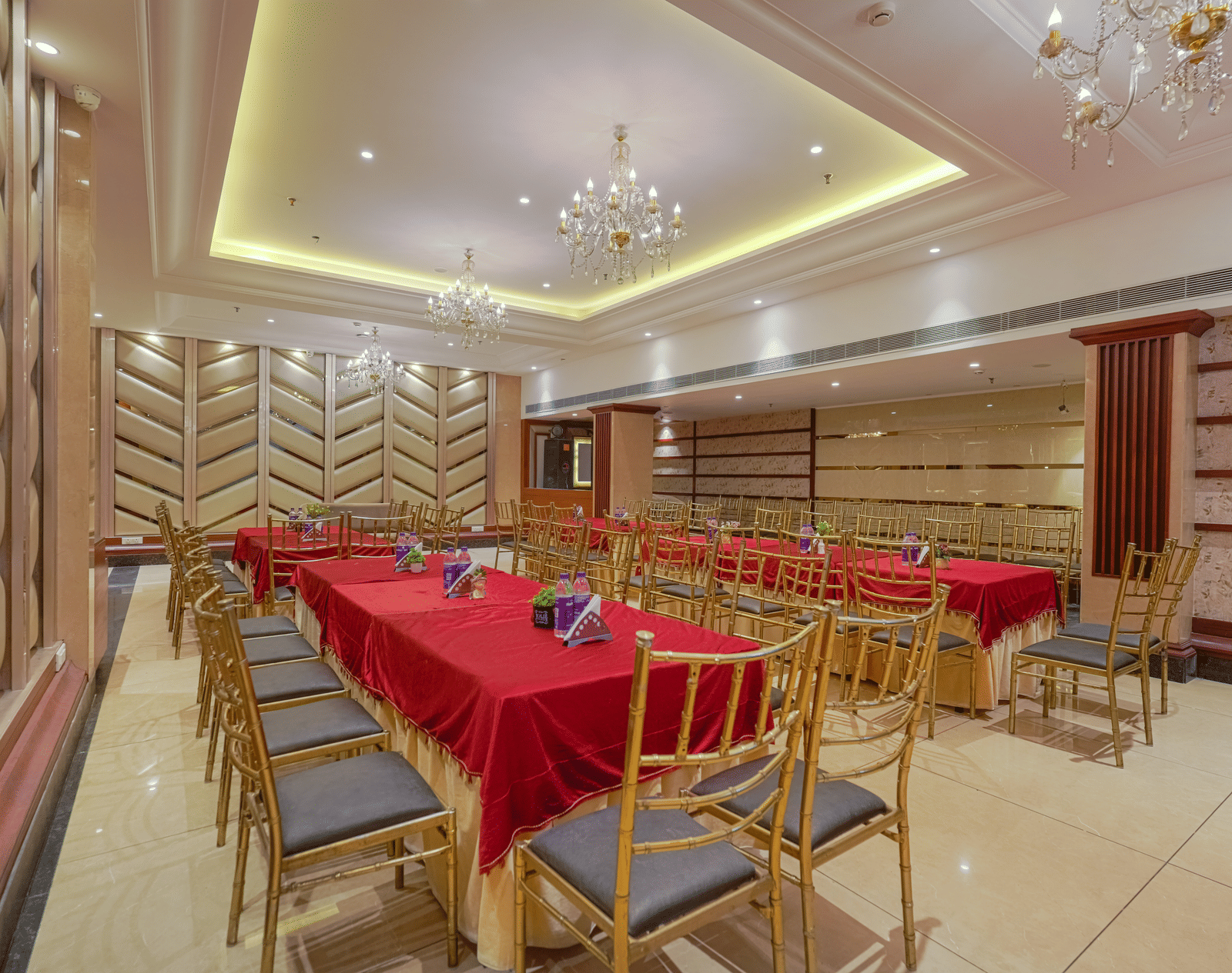 A luxury private dining or conference room with a long table covered in a red cloth, surrounded by gold and grey chairs at BluSalzz Select City Centre, Amritsar.