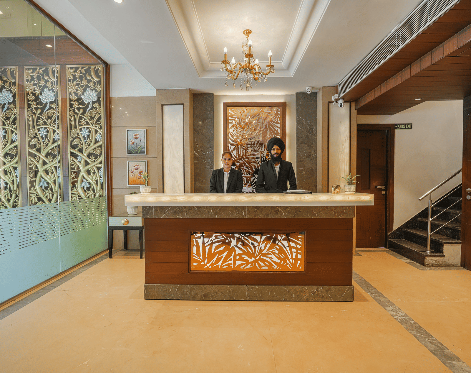 A wider view of the ornate hotel reception area, showing the decorative desk, a staff member, and luxurious wall panels at BluSalzz Select City Centre, Amritsar.