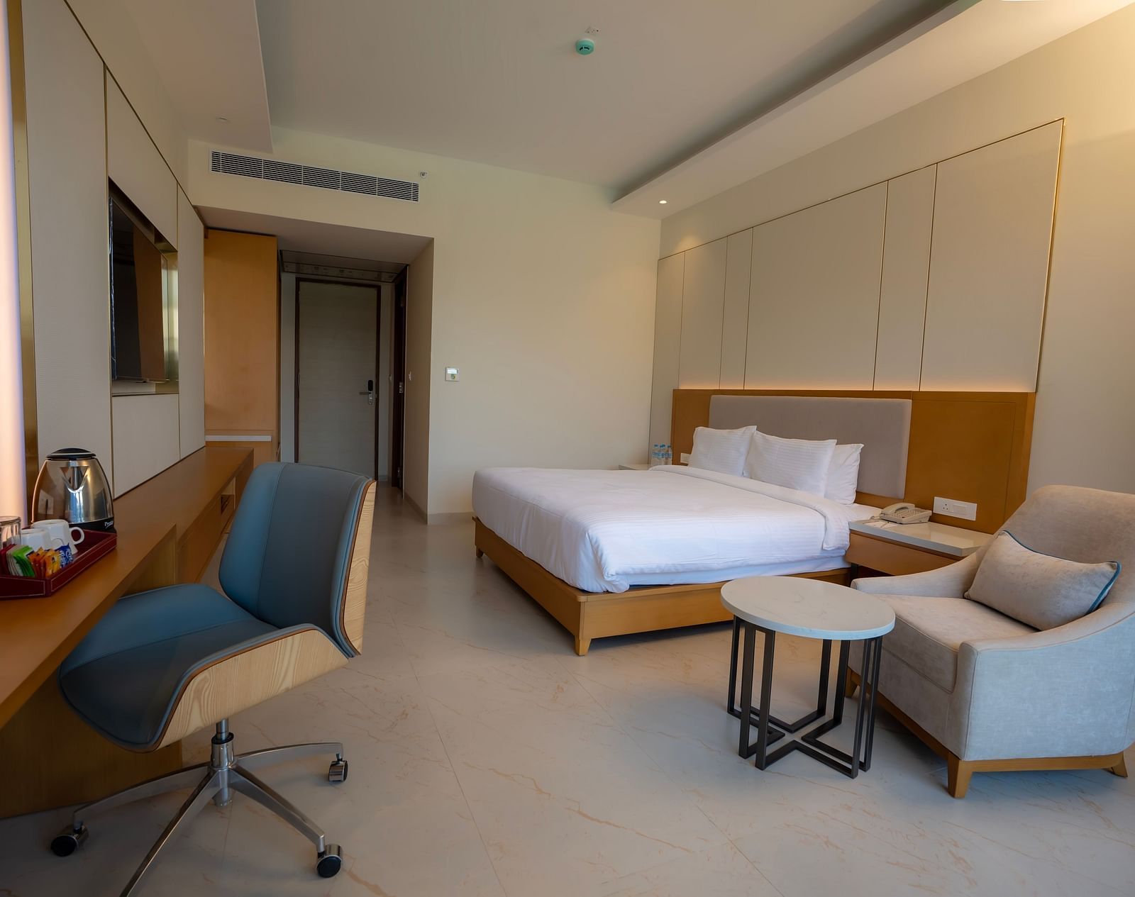 Interior of the Pool View Bliss featuring modern furnishings along with a double bed and an armchair beside it with a table at The Shore, Trishvam.