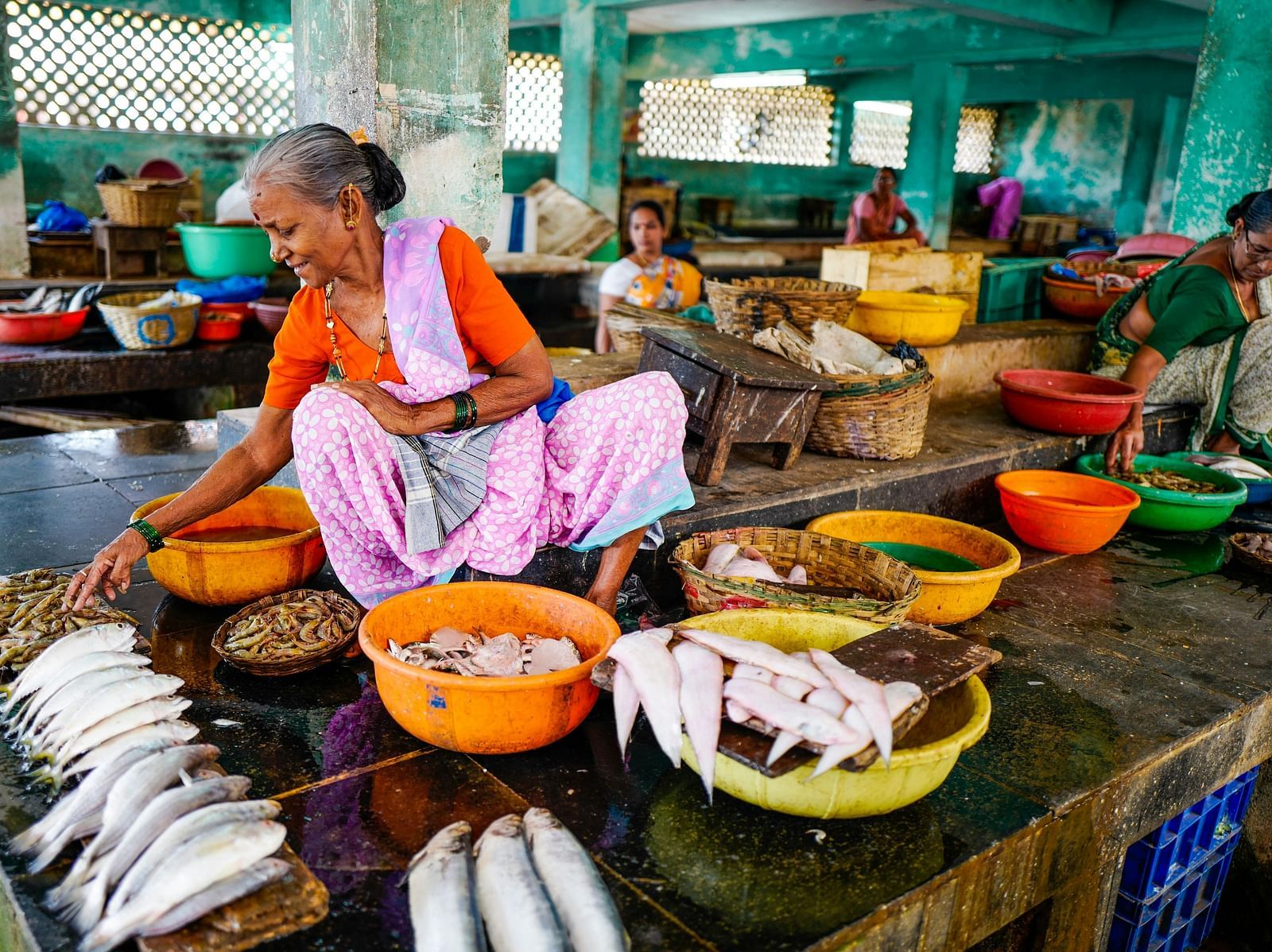 Women in the market assorting sea food items.