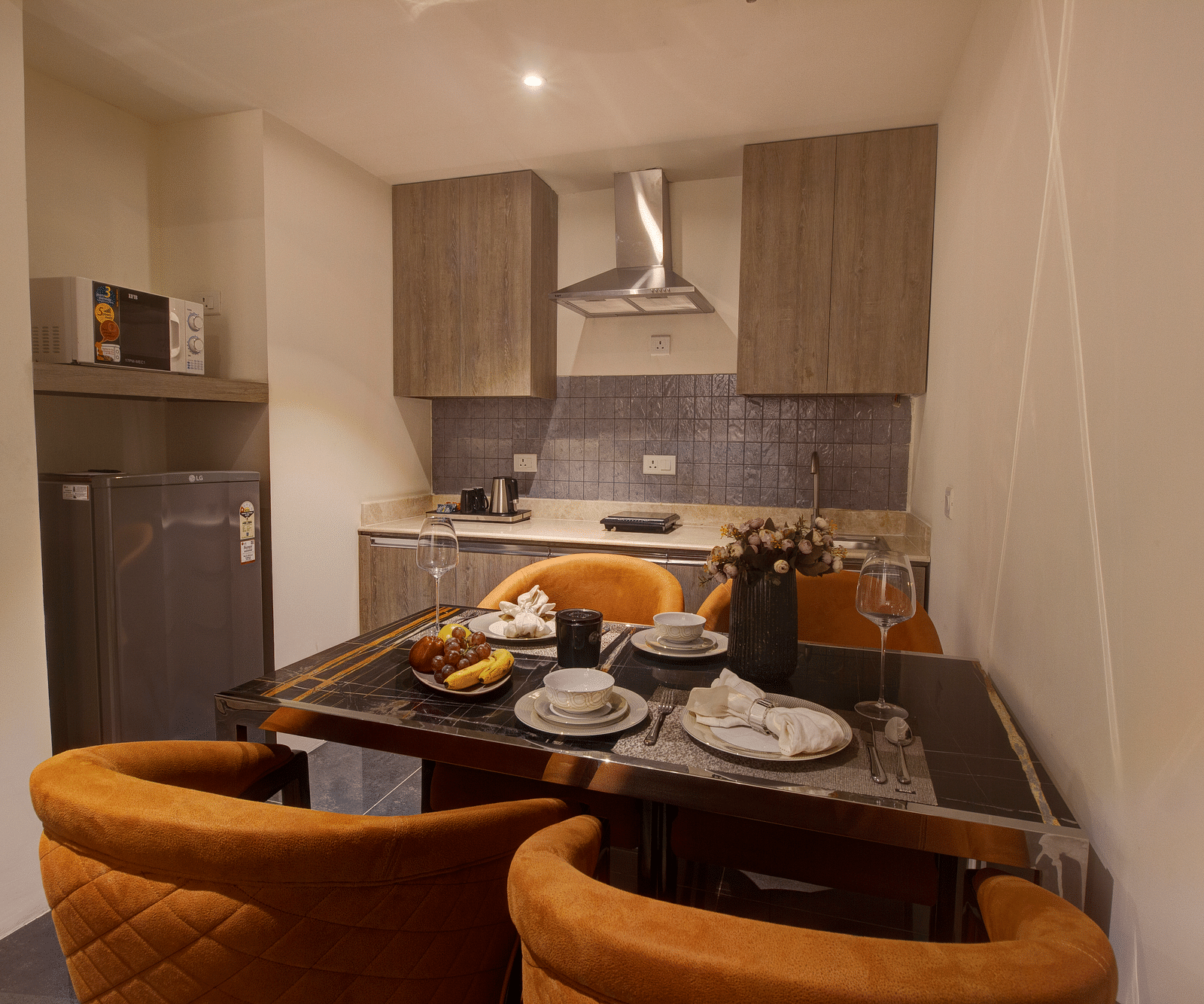 A dining table with a kitchen in the background of Two bedroom Executive Suite - Rhythm Gurugram