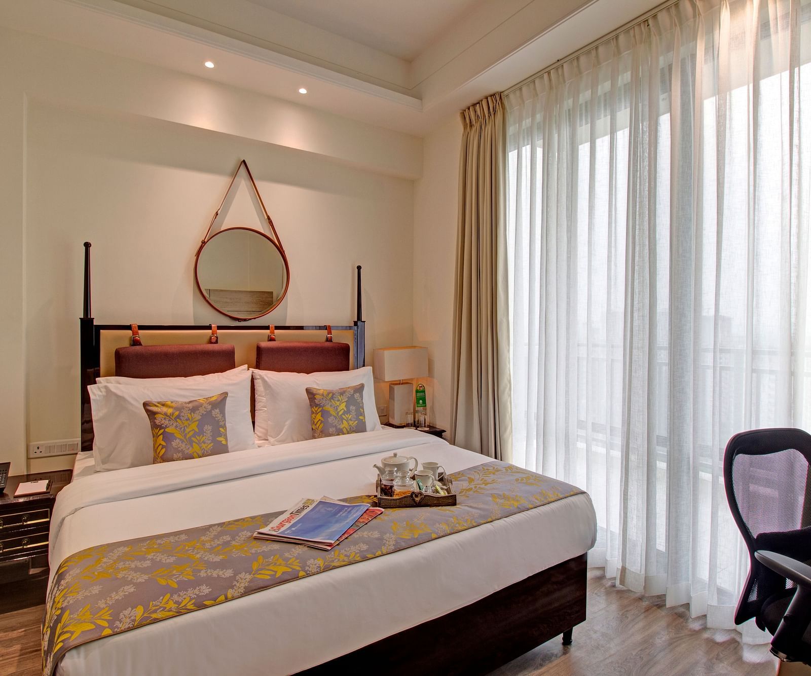 a king bed with side tables and a study desk opposite the bed inside Deluxe Suite at Rhythm Gurugram