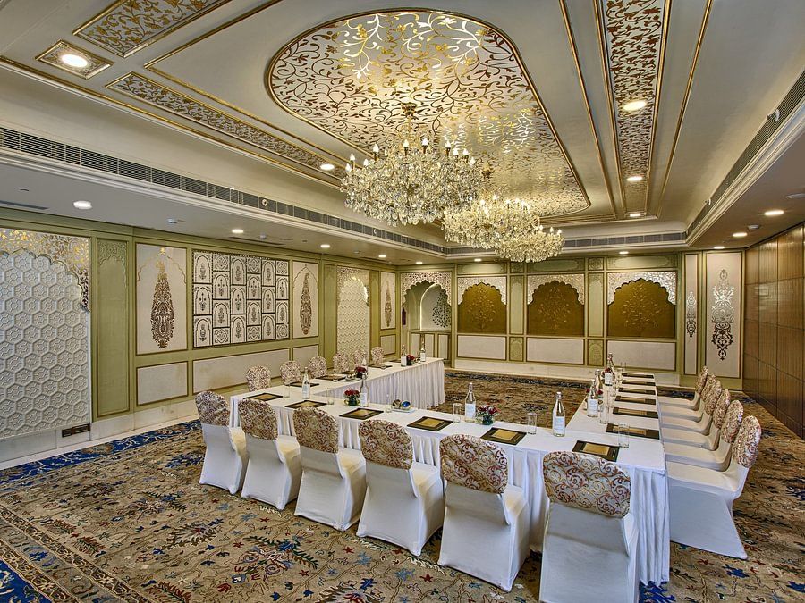 Elegant meeting room with a U-shaped table, ornate ceiling, chandeliers, and patterned carpet - Heritage Village Resorts & Spa.