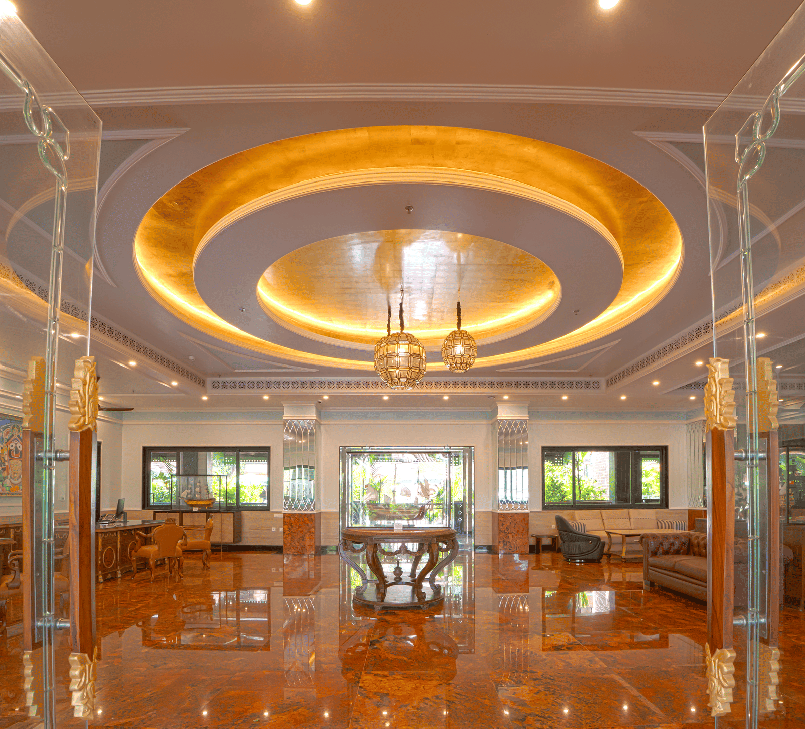 A luxurious indoor space with high reflective flooring, circular illuminated ceiling feature, chandeliers, glass partitions and lounge seating at MAYFAIR Bay Resort, Paradeep.