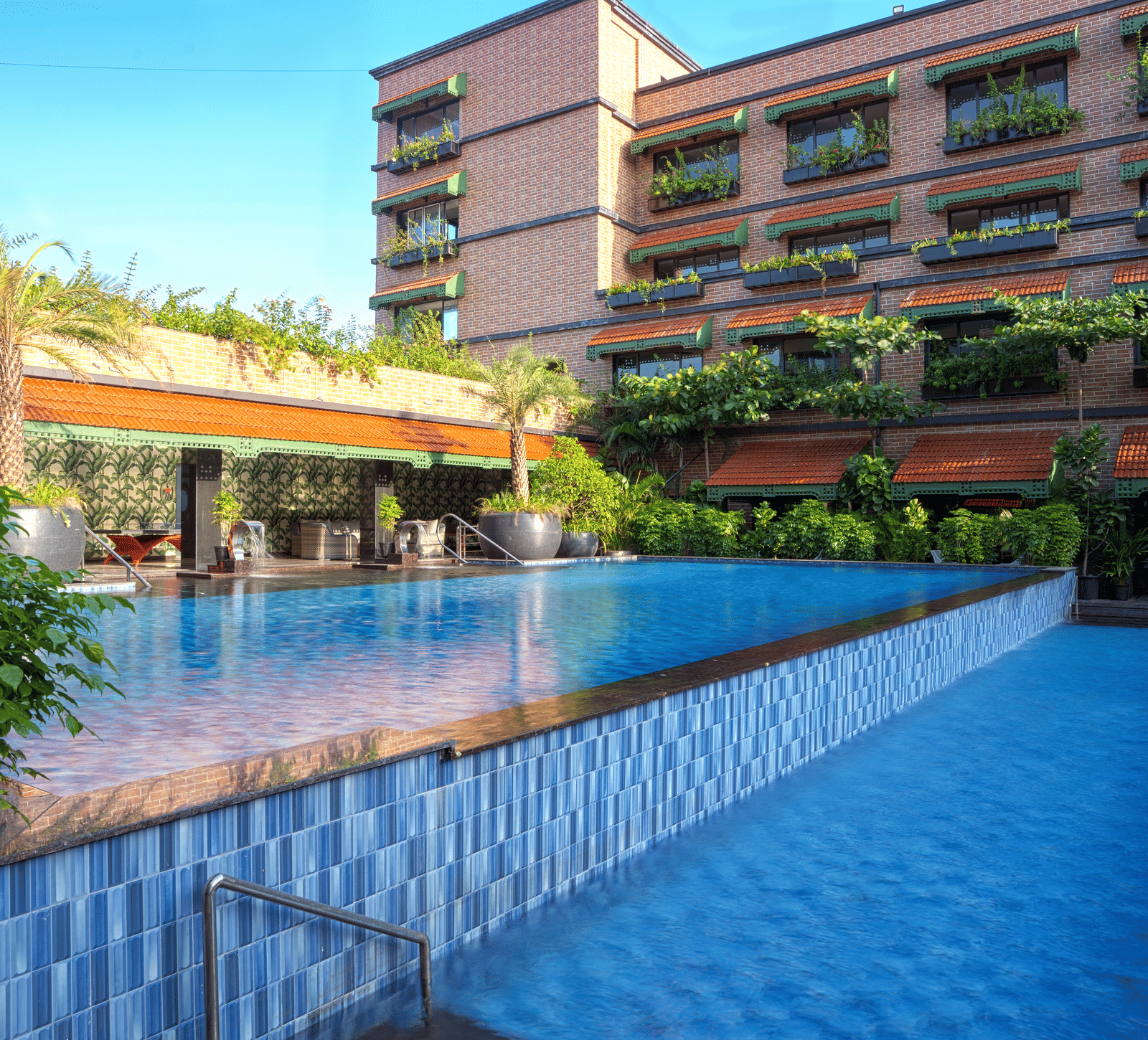 Exterior view of MAYFAIR Bay Resort, Paradeep's building with dark cladding, overlooking a rectangular swimming pool.
