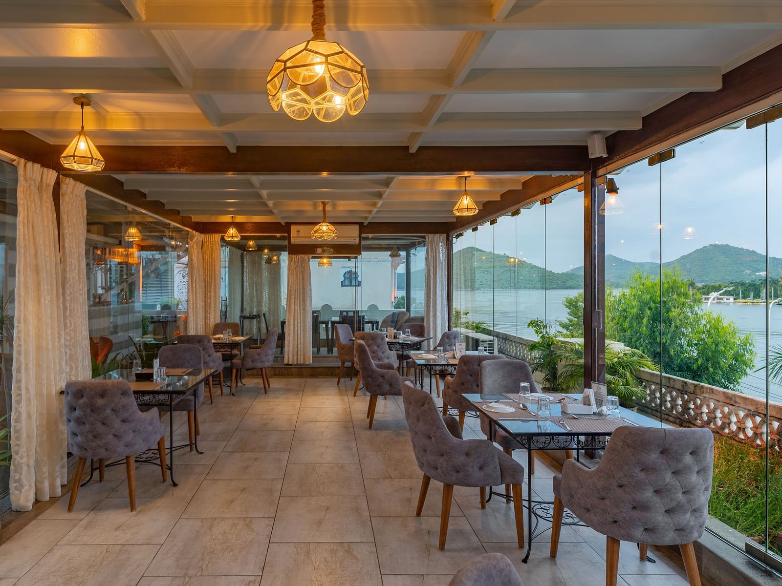 Restaurant area at Panna Vilas Palace showcases a four-seater table with wooden chairs, enhanced by warm lighting and the presence of potted plants | Panna Vilas Udaipur