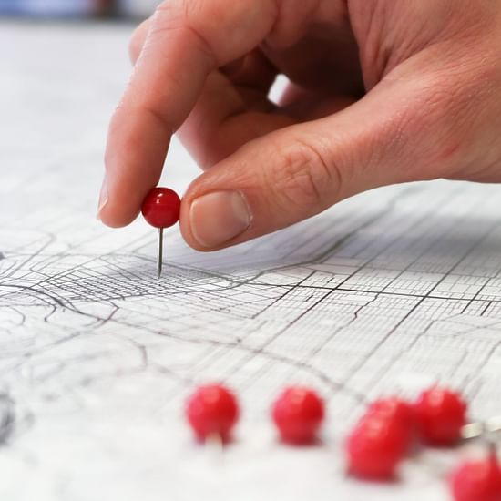 a person putting a pin on a map with other red pins on the side
