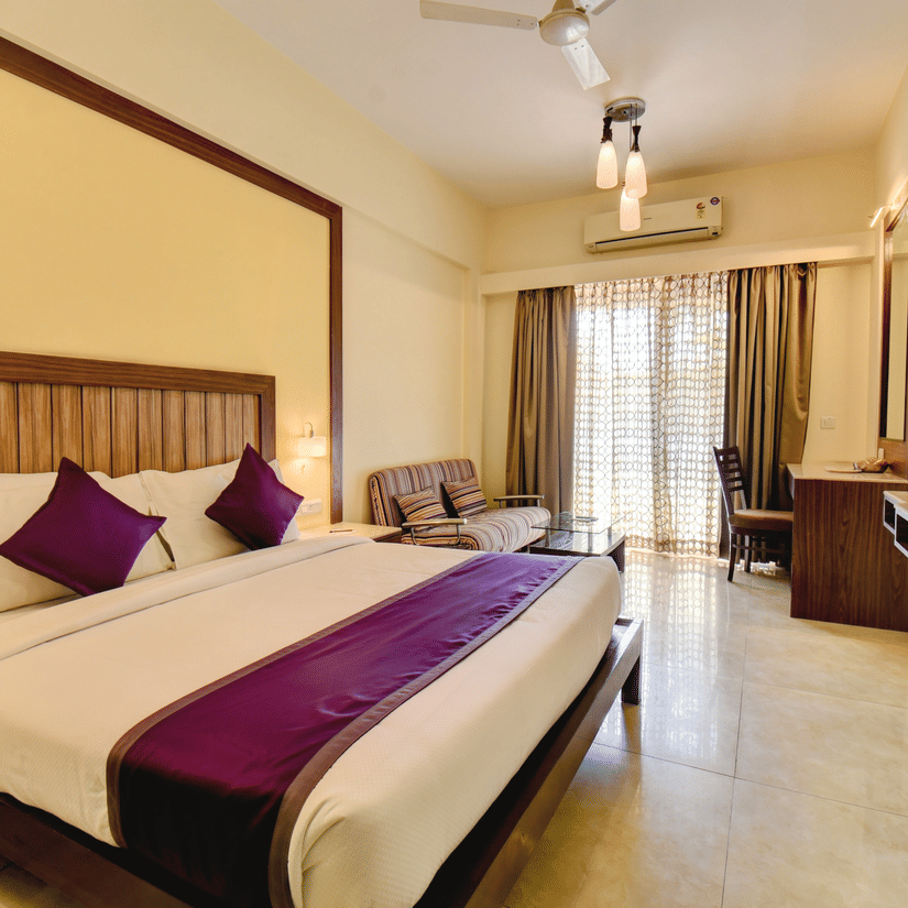Spacious executive room with king-size bed, purple accents, and balcony at VITS Lonavala.