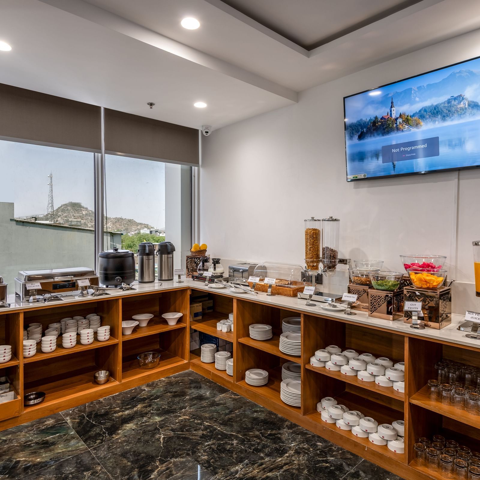 A BCR buffet area featuring a selection of breakfast foods, neat and tidy worktops, TV on the ceiling and a glass windows