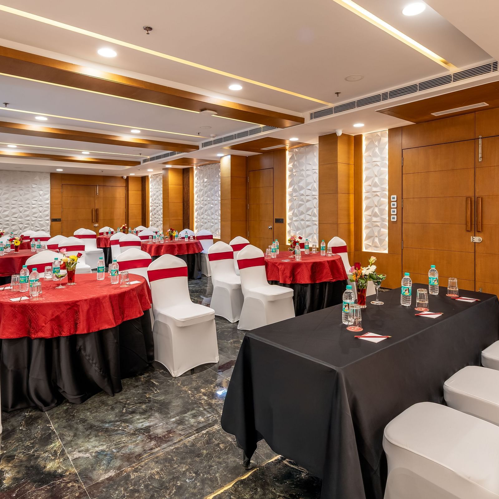 Banquet sitting setup with round and rectangular tables, red and white chair covers, and wood-paneled walls.