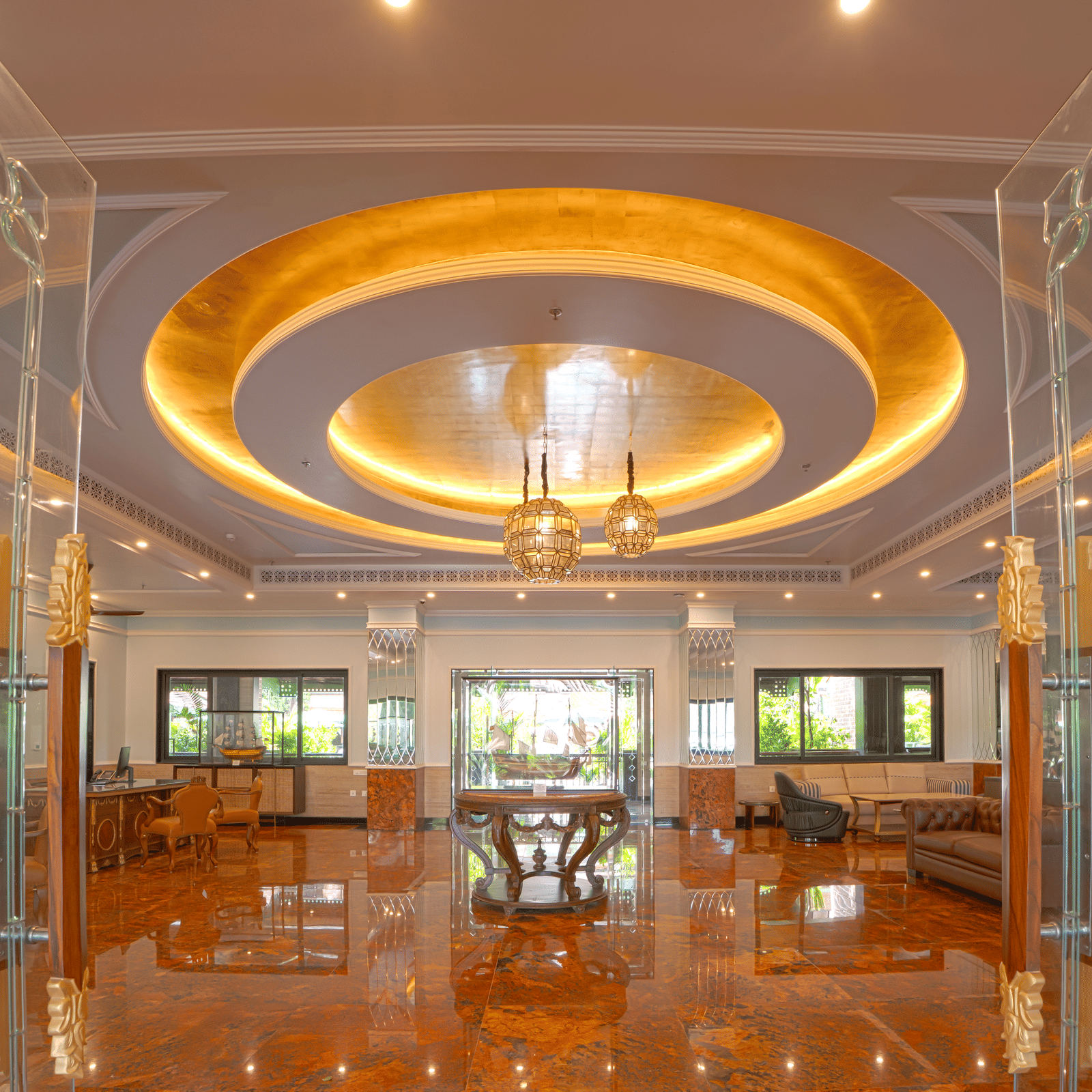 A luxurious indoor space with high reflective flooring, circular illuminated ceiling feature, chandeliers, glass partitions and lounge seating at MAYFAIR Bay Resort, Paradeep.
