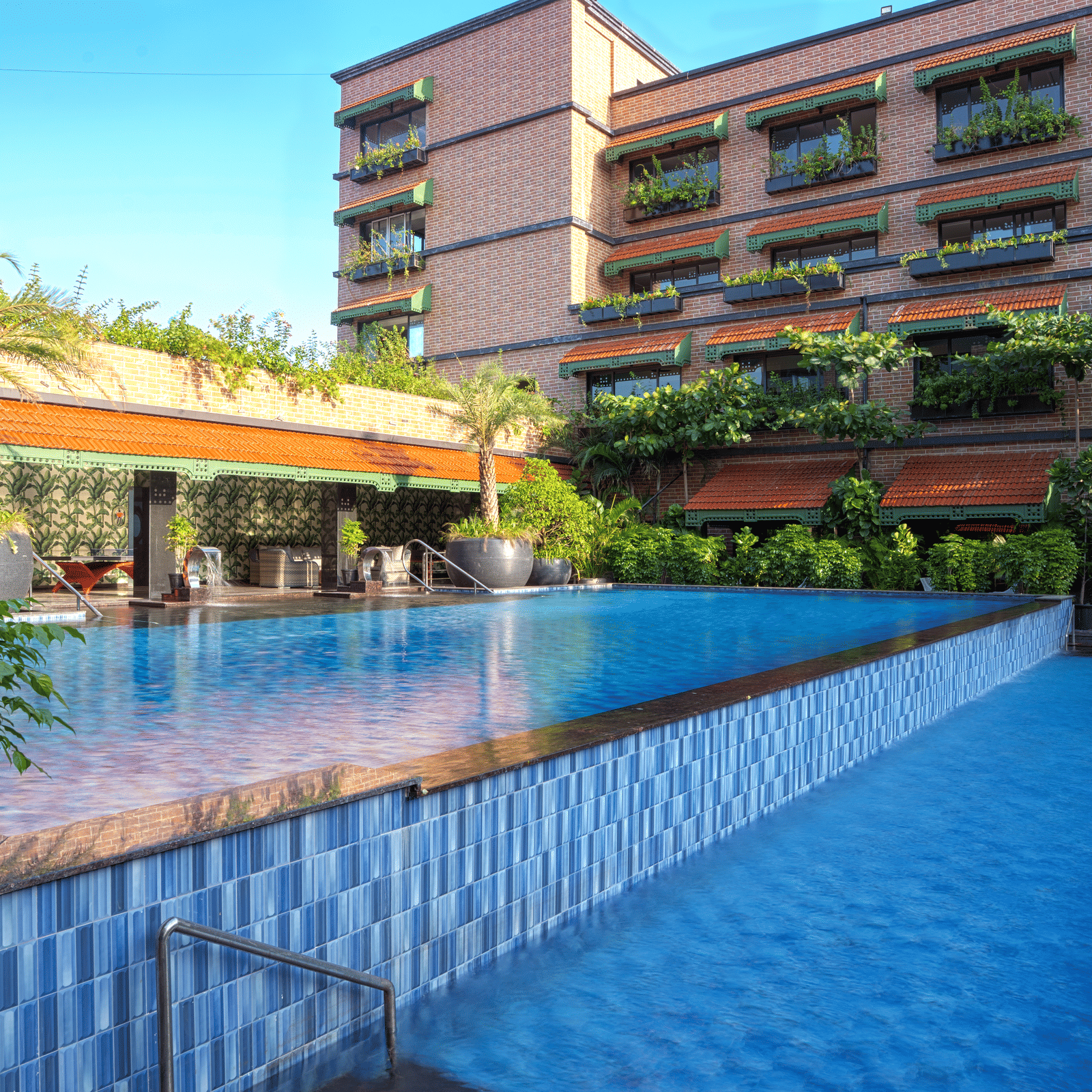 Exterior view of MAYFAIR Bay Resort, Paradeep's building with dark cladding, overlooking a rectangular swimming pool.