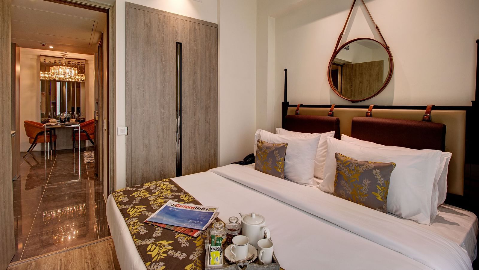 a king bed with many pillows and a bed runner inside the Deluxe Room - Rhythm Gurugram