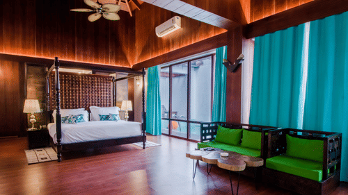 an overview of the Beach Mansion with a king bed in the centre and a tv and sofa on either side - Symphony Summer Sand Beach Resort And Spa, Neil Island