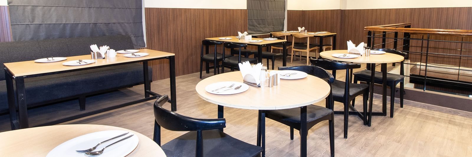 A dining area set up with tables and chair in a warm lit ambience - Sanctum Suites Richmond Road, Bangalore