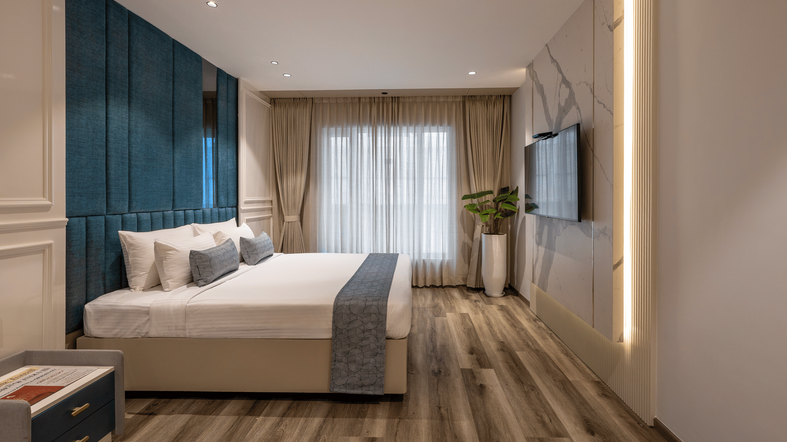 A room at the Citrine Hotel with a bed, a TV mounted on the wall, and a large window.