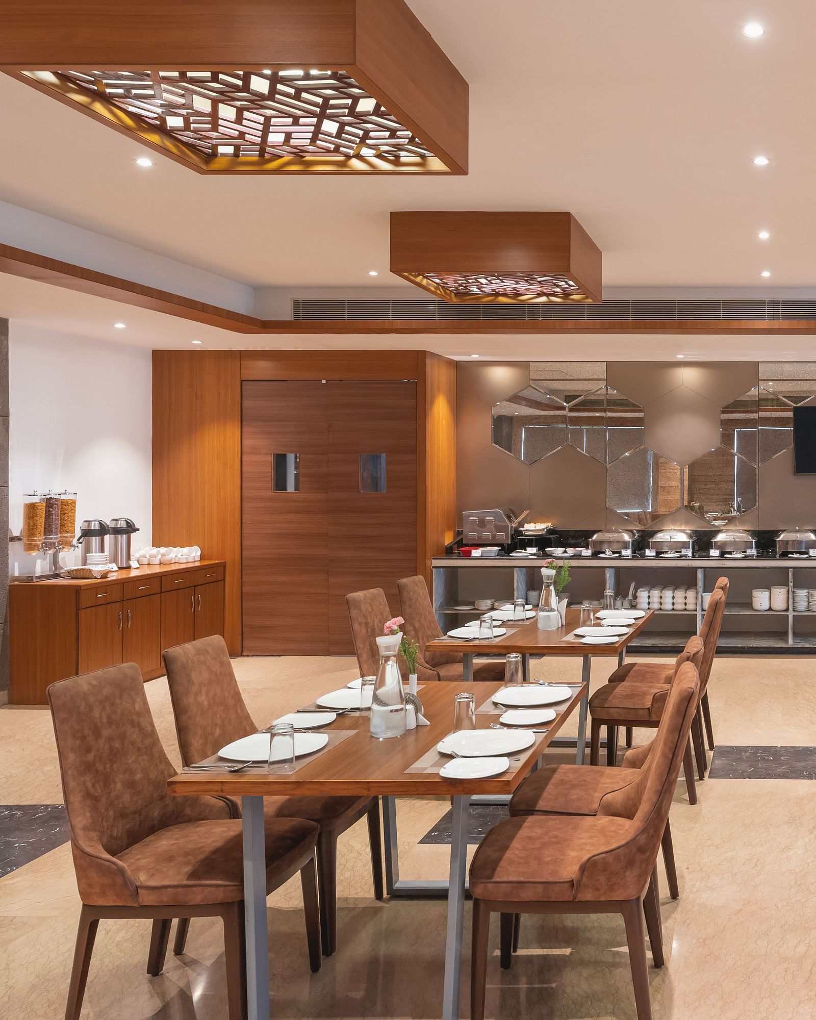 The spacious restaurant at Lords Inn Udaipur is set with multiple tables and chairs, featuring a buffet area in the background.