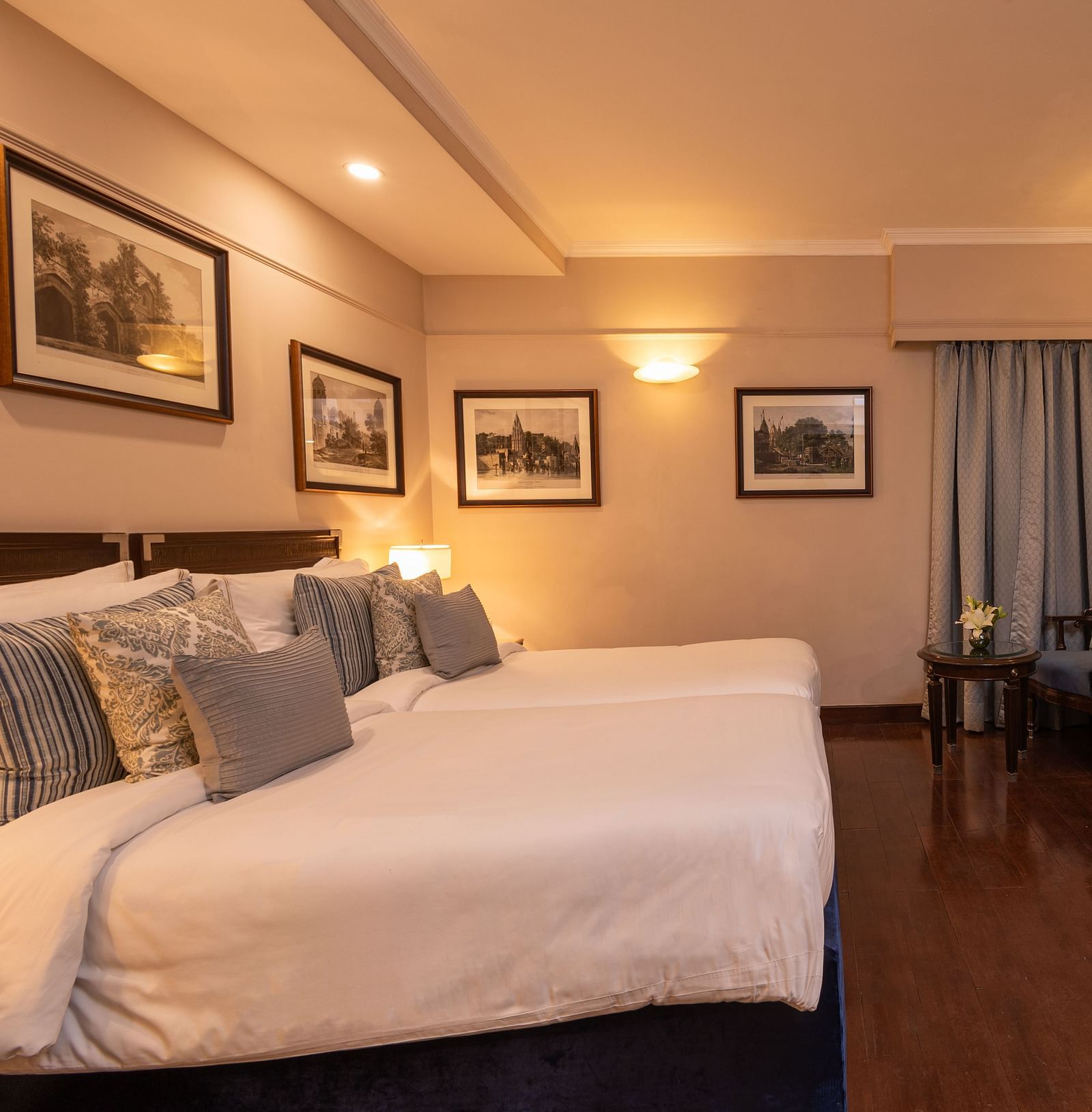 Side view of the Superior Twin Bed Room at The Claridges New Delhi, showcasing twin beds, a wall-mounted TV, and bedside lamps