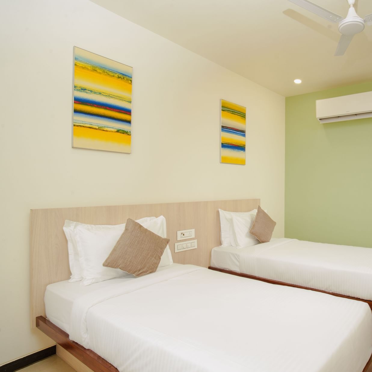Hotel room interior with three beds and an air conditioning unit at Arawali Ananta Elite, Jaipur.