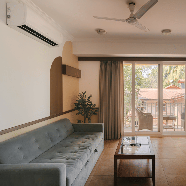 Well-lit living room with a cozy seating area and a balcony at the Two BHK apartment in Richmonde Ananta Elite, Goa.