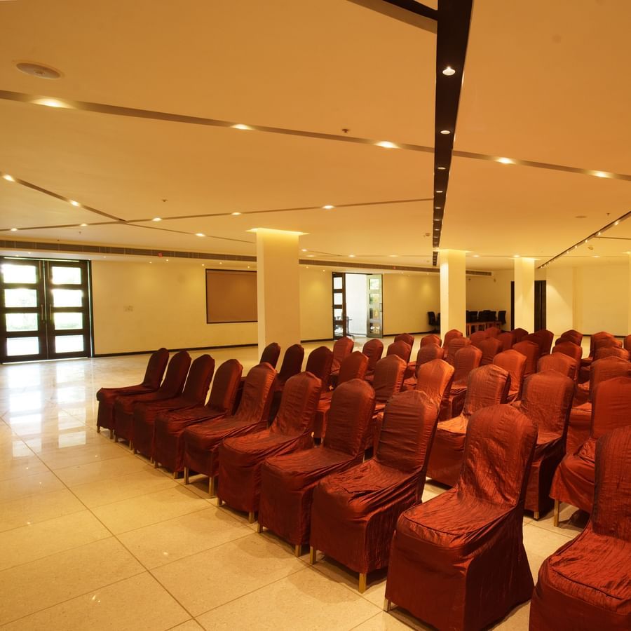 Large banquet or conference hall set up with rows of red chairs for an event at Arawali Ananta Elite, Jaipur.