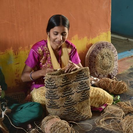 Two women crafting intricate items from natural fibers.